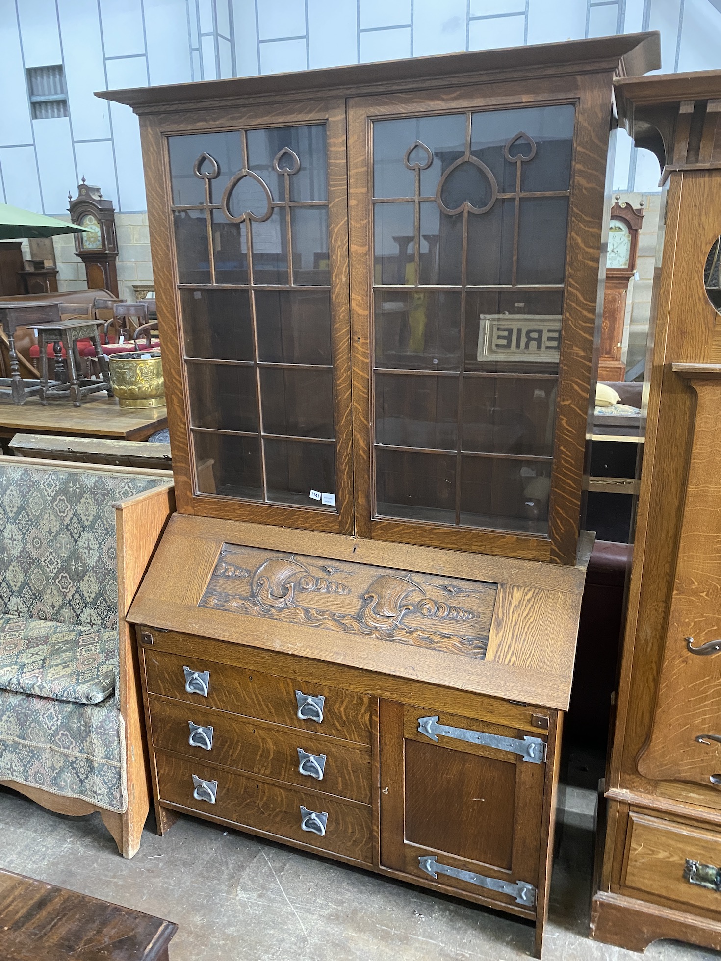 An Arts & Crafts oak bureau bookcase carved with Viking longboats, width 122cm, depth 48cm, height 213cm